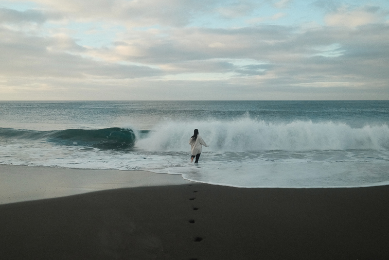 Black sand beach in São Miguel, person running towards the ocean